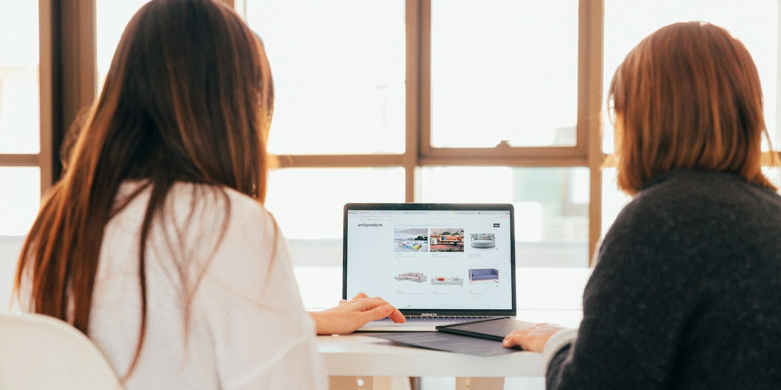 two women talking while looking at laptop computer