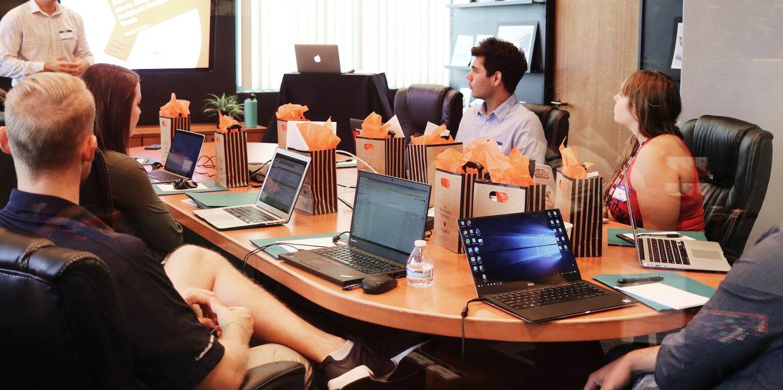 man standing in front of people sitting beside table with laptop computers