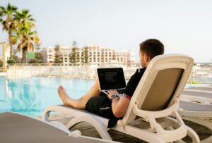 man on sun lounger using laptop